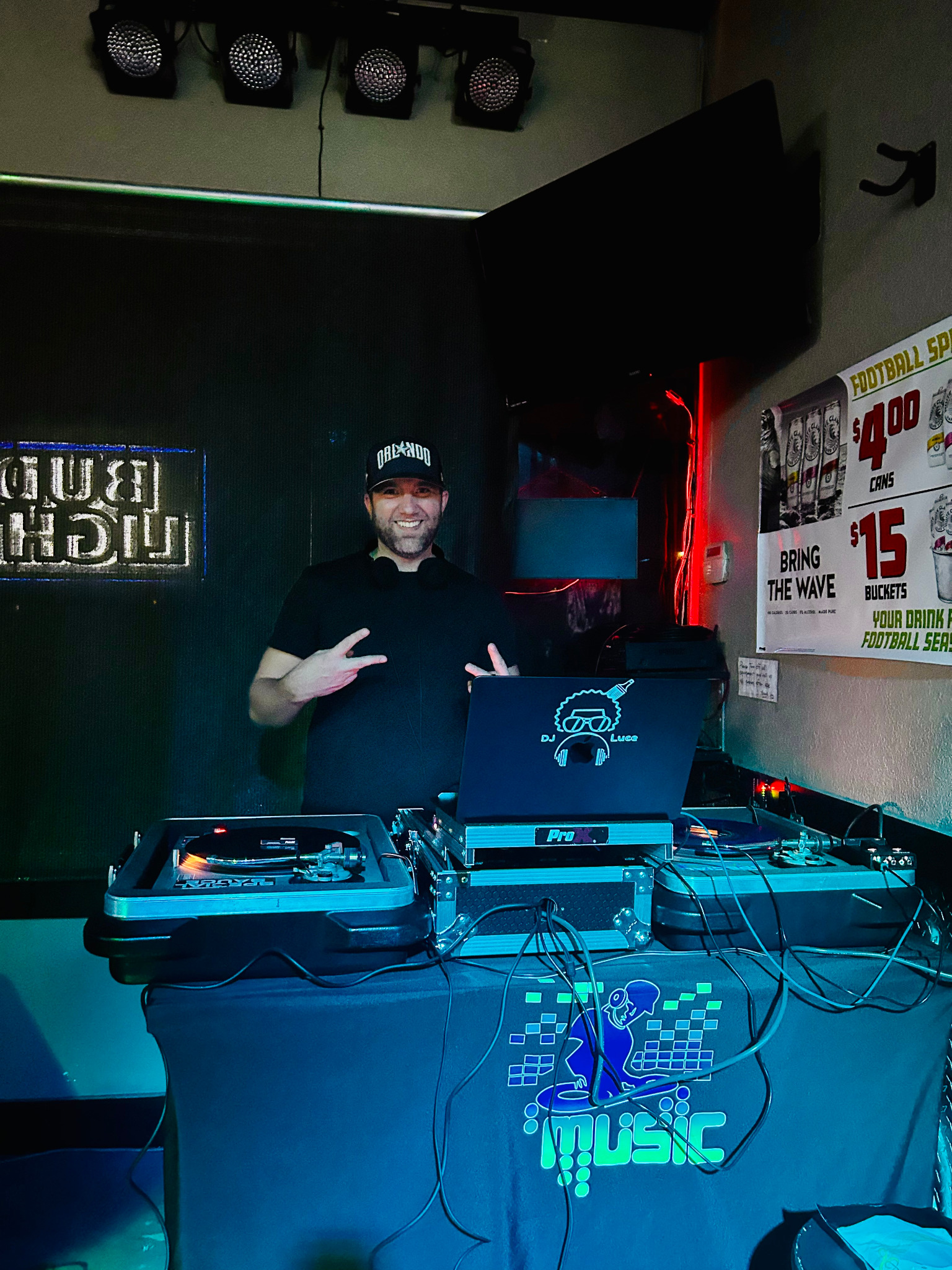 DJ Luce performing behind turntables under club lights