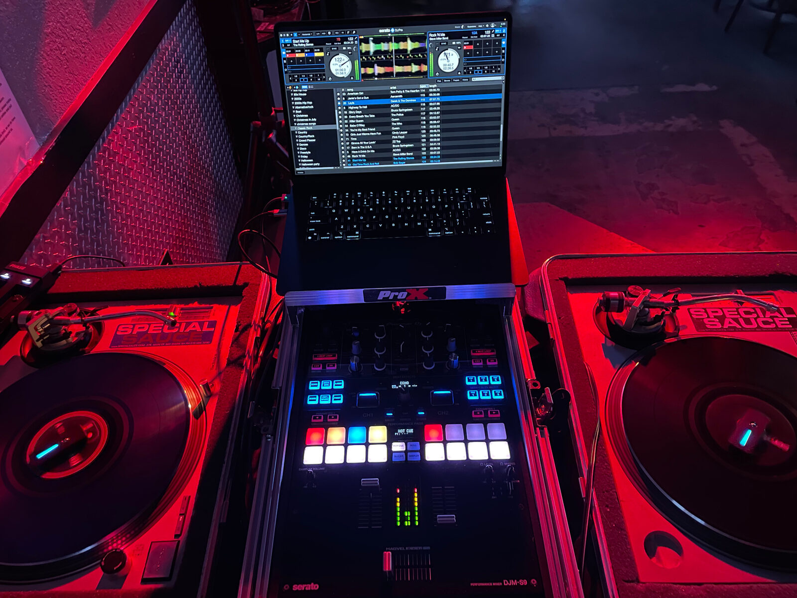 DJ Luce turntables and mixing equipment under red lighting